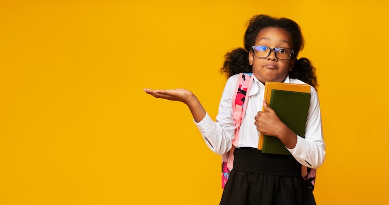 Puzzled School Girl Shrugging Shoulders Holding Books On Yellow Background