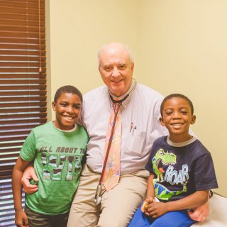 Dr. Harper posing with two smiling boy patients in their office