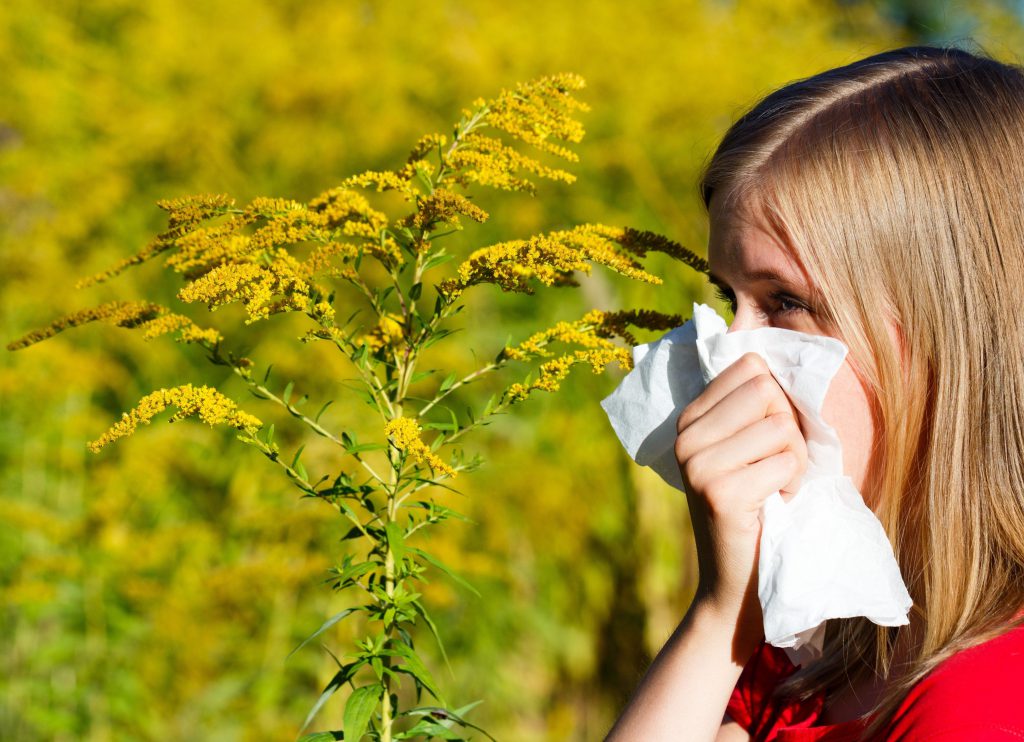 Woman blowing nose in field