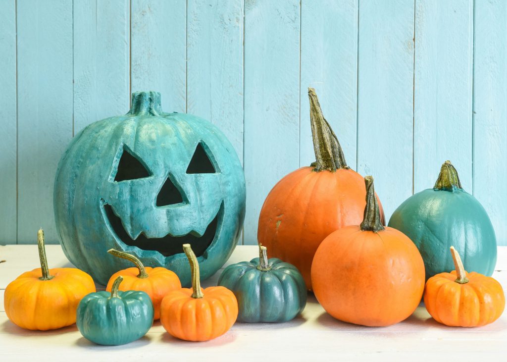 Assortment of orange and teal pumpkins sitting on a counter