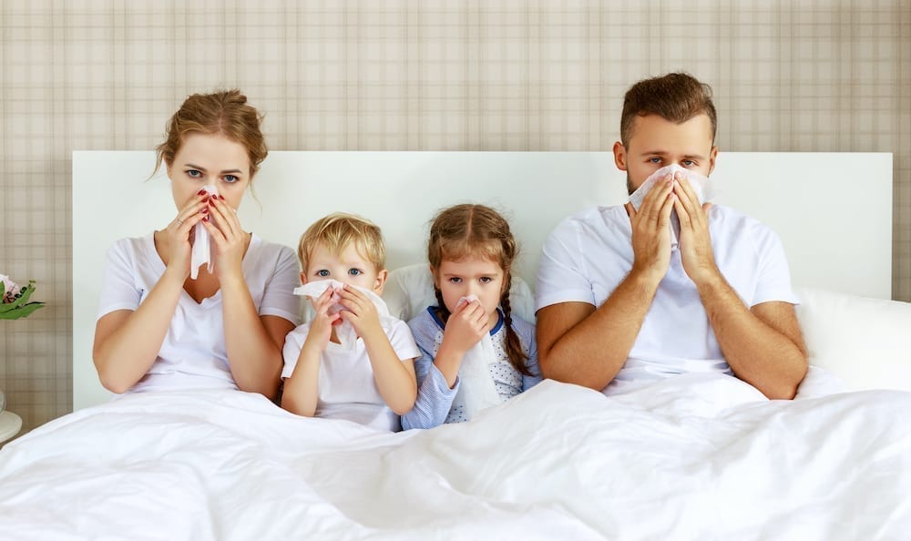Family blowing their noses while in bed