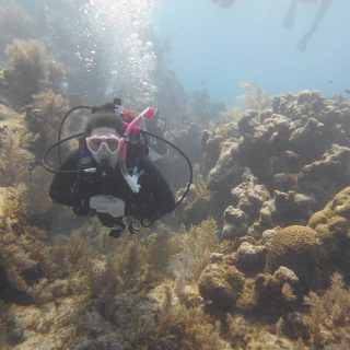 Dr. Steadman scuba diving underwater in front of coral