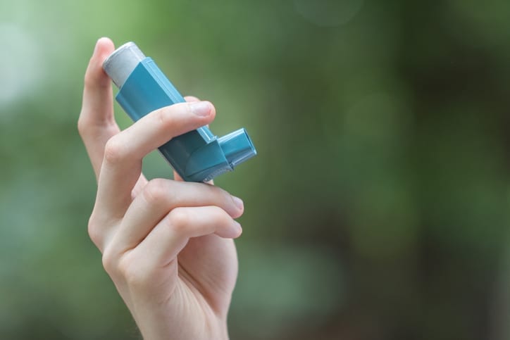 Asthma medicine inhaler held by a man
