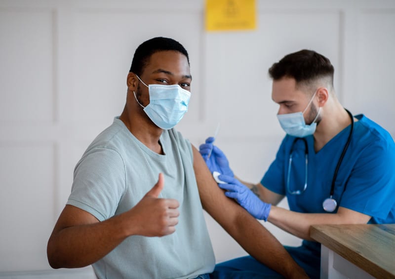 Patient giving a thumbs up while the nurse gives him a shot