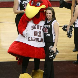 Dr. Steadman in her USA cheerleading outfit with the USC Gamecock mascot at a basketball game