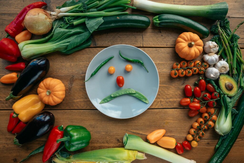 Vegetables on a table and the ones on the plate are making a sad face