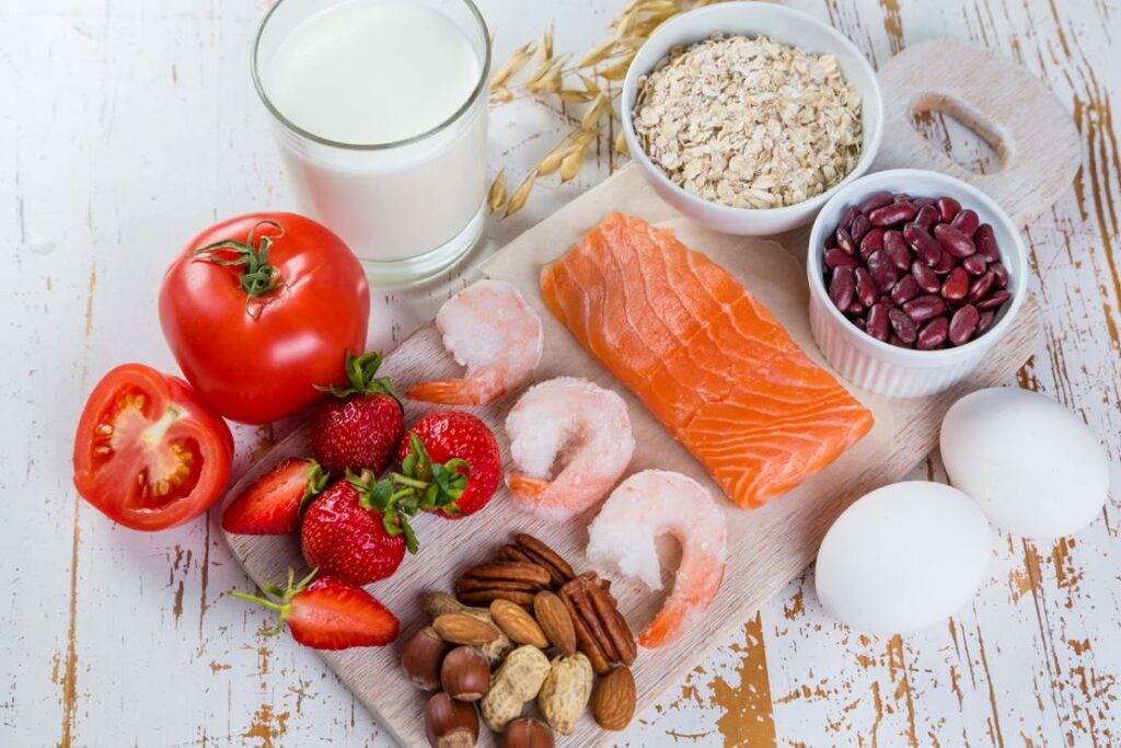 Foods that typically cause allergies on a board including milk, tomato, starberries, nuts, shrimp, salmon, eggs, oat and beans