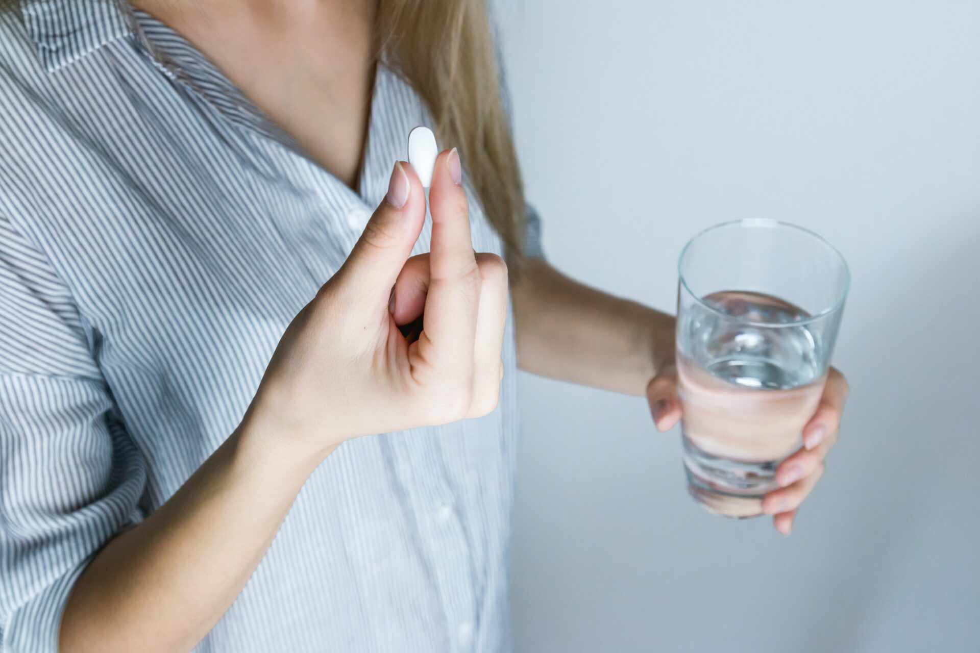 woman with pill and glass of water