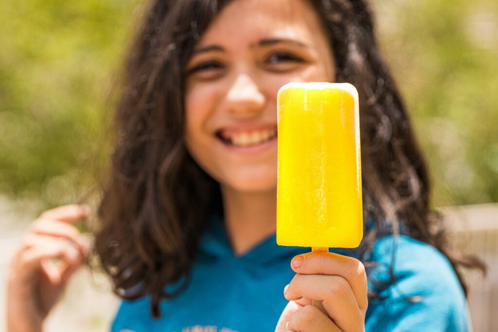 Little girl holding a yellow popsicle