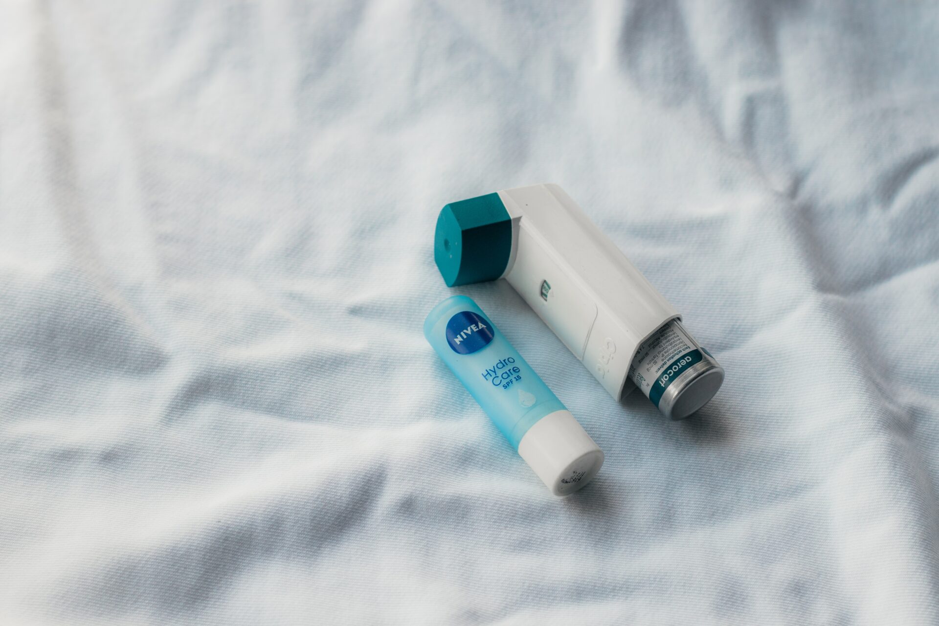 Nivea Hydro-Care lip balm sitting next to an inhaler on a white sheet