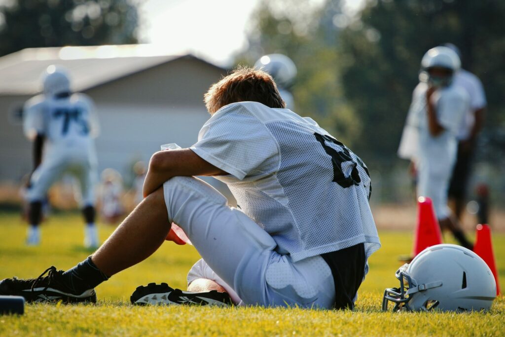 Tired football player sitting on the field