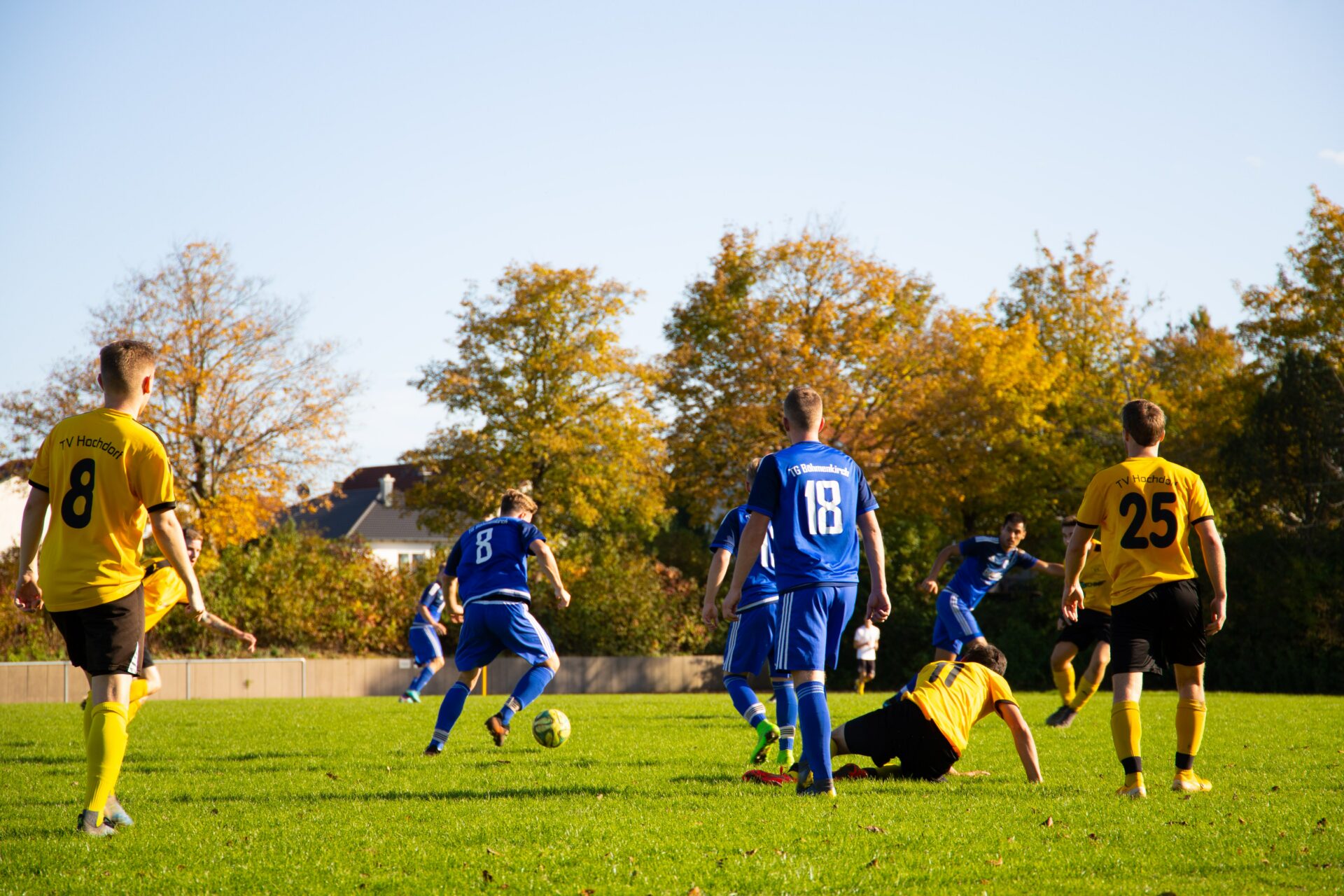 Two soccer teams wearing blue and yellow going after the soccer ball