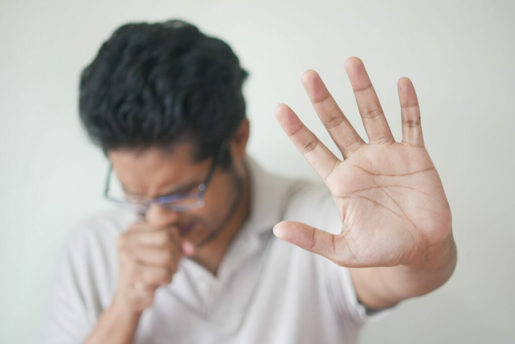 Man holding his hand out and sneezing.